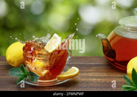 Zitronenscheibe, die in eine Tasse Tee fällt Spritzer Stockfoto