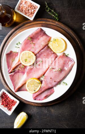 Frische Tintenfische oder Tintenfische für gekochte Speisen. Frischer roher Tintenfisch. Roher Tintenfisch mit Zitrone. Draufsicht und Kopierbereich für Ihren Text Stockfoto