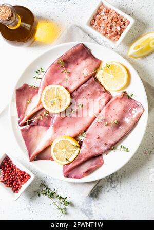 Frische Tintenfische oder Tintenfische für gekochte Speisen. Frischer roher Tintenfisch. Roher Tintenfisch mit Zitrone. Draufsicht und Kopierbereich für Ihren Text Stockfoto
