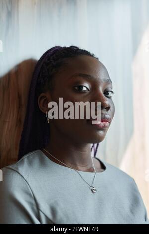 Grafisches Kopf- und Schulterporträt einer selbstbewussten afroamerikanischen Frau Bei der Kamera, während man im Sonnenlicht am Fenster steht Stockfoto