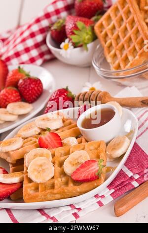 Waffeln mit Erdbeeren, Bananen und Honig. Stockfoto