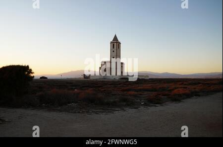 Sonnenuntergang in Las Salinas, Naturpark Cabo de Gata, Almeria, südlich von Spanien, mit Kirchturm. Stockfoto