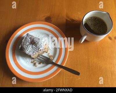 tasse schwarzen Kaffee und ein Stück Kuchen mit einem Gabelstapler davon Stockfoto