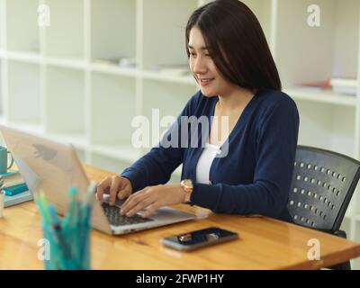 Eine kurze Aufnahme einer Studentin, die mit einem Laptop arbeiten möchte Und Schreibwaren in der Bibliothek Stockfoto