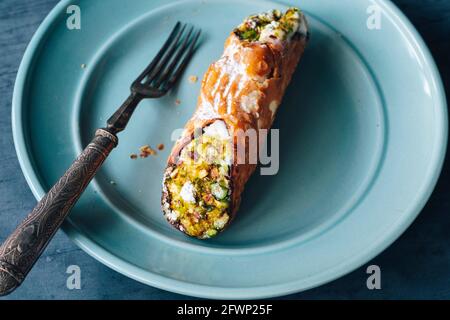 Pistazien Cannoli gefüllt mit Frischkäse und bestäubt mit Glasur auf einer dekorativen Platte mit Gabel - FOODPIX, Textraum, Platz für Text Stockfoto