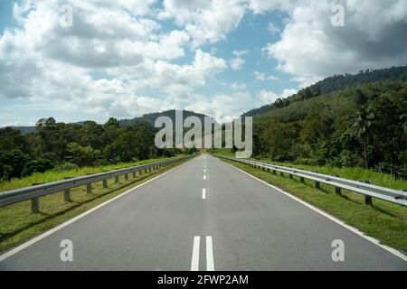 Straße und Sommer Bergkette Landschaft mit grünem Gras Wald, blauer Himmel, natürliche Outdoor-Reise Hintergrund, bewölkten Tag, Asphaltstraße in der Mitte, Ma Stockfoto