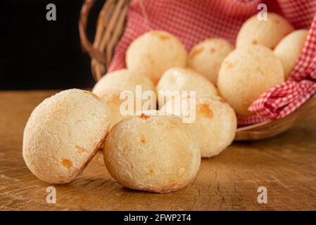 Brasilianisches Käsebrot, Korb mit kariertem Tuch mit Käsebrot auf rustikalem Holz, selektiver Fokus. Stockfoto