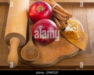 Honiglöffel, Glas Honig, Äpfel und Zimt auf einem Holzhintergrund in einem rustikalen Stil Stockfoto