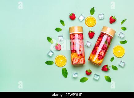 Erdbeerwasser, Cocktail, Limonade oder Tee. Sommerlich eisgekühltes Getränk mit Erdbeere, Zitrone und minze auf grünem Hintergrund. Flach liegend Stockfoto