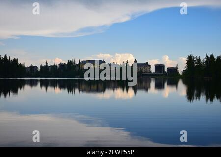 Strbske pleso, See und Kleinstadt, am Abend. Gebäude und Bäume spiegeln sich im Wasser. Hohe Tatra, Slowakei. Bild aus öffentlichem Boden Stockfoto