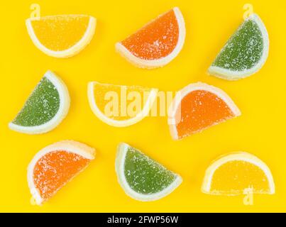 Bunte Marmelade Zitrusscheiben in Zucker auf gelbem Hintergrund. Stockfoto