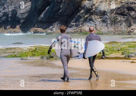 Mawgan Porth Beach in Cornwall in Großbritannien; Surfer mit ihren Surfbrettern, die während eines Aufenthalts in Cornwall zum Meer laufen. Stockfoto