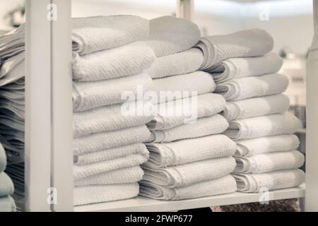 Drei Stapel weißer Handtücher auf einem Regal in einem Geschäft für Bettwäsche und Textilien. Stockfoto