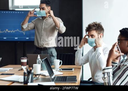 Internationale Menschen tragen medizinische Masken bei der Arbeit Stockfoto