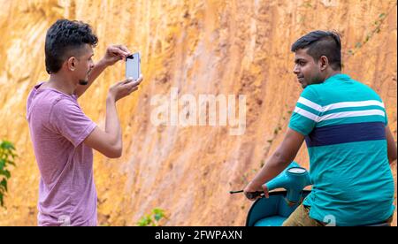 Galle, Sri Lanka- 06 21 2020: Freund, der ein Portraitbild eines jungen Mannes auf einem Roller von einer Handykamera aus macht. Stockfoto