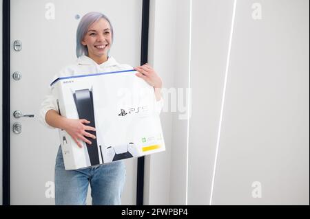 Frau überrascht ihren Bruder mit einer Sony playstation 5-Konsole der nächsten Generation, Online-Shopping-Geschenk, moderne Videospiel-Gerät für Cyber-Sport. Moskau – Nein Stockfoto