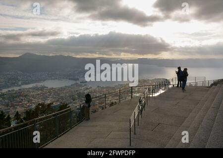 Bergen, Norwegen - 24. Mai 2017: Touristen, die an einem nebligen Sommernachtssommer von einer Aussichtsplattform auf dem Berg Floyen aus die Aussicht auf Bergen genießen Stockfoto