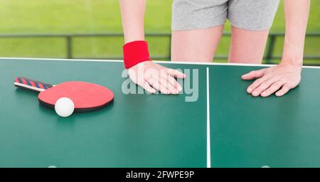 Zusammensetzung der mittleren Sektion der weiblichen Tischtennisspielerin, die sich lehnt Auf dem Tisch mit Ball und Schläger Stockfoto