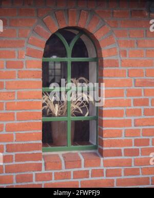 Altes Fenster in einer Ziegelwand mit Blumen Stockfoto