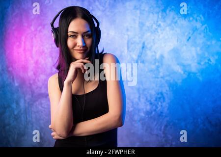 Lächelnde Frau das Headset mit Mikrofon suchen Zeigefinger an der Kamera, die Sie auf Neon farbigen Hintergrund. Stockfoto