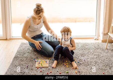 Die Gelassenheit der Mutter ist der Schlüssel zum Erfolg in den Beziehungen zu kleinen Kindern. Der 3-jährige Junge ist frech und weint. Mama beruhigt ihn mit einem Lächeln Stockfoto