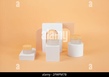 Glasgläser aus Bio-Creme sind auf einem Podium in Pastelltönen gehalten. Hintergrund für Branding- und Verpackungspräsentation. Kosmetisches Kosmetikprodukt Stockfoto