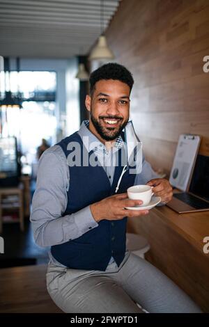 Geschäftsmann mit Kaffee, der im Café arbeitet, freiberuflich arbeitet und das Coronavirus-Konzept. Stockfoto