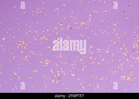 Fallendes goldenes funkelt, Konfetti auf purpurem Feiertagshintergrund. Festliche Kulisse für Partys, Feiern und Geburtstage. Stockfoto