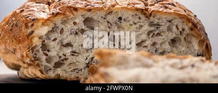 Banner mit in Scheiben geschnittenem Brot auf dem Servierbrett mit Flachs- und Sonnenblumenkernen. Frisches, leckeres, rundes Weizenbrot mit Leinsamen auf weißer Struktur Stockfoto