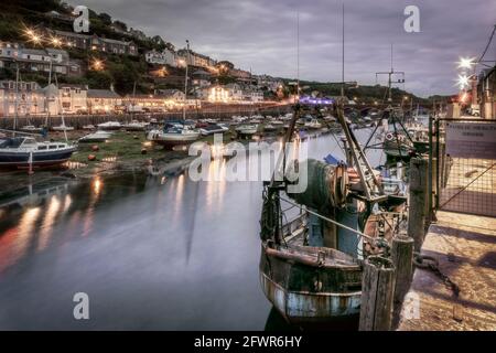 Nach dem anderen kühlen bewölkten Tag die Lichter flackern auf wie das Tageslicht in der Dämmerung in der historischen Fischerhafen von Looe, Cornwall. Stockfoto