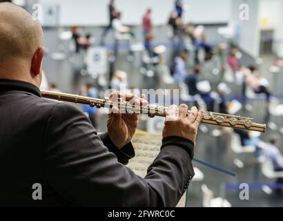 24. Mai 2021, Hessen, Frankfurt/Main: Der Flötist Walter Dorn von der Kammeroper Frankfurt/Main spielt am Nachmittag auf dem Balkon im Impfzentrum in der Festhalle, um an diesem ungewöhnlichen Ort eine Reihe von 16 Konzerten zu starten. Die Frankfurter Kammeroper möchte nach eigenen Angaben die Befürchtungen oder Beunruhigung derer, die angesichts des Unbekannten warten, ein wenig wegnehmen. Die Konzerte finden zwischen 3 und 6 Uhr statt. Foto: Frank Rumpenhorst/dpa Pool/dpa Stockfoto