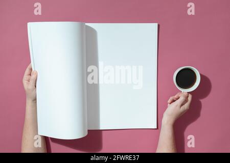 Komposition einer kaukasischen Frau, die ein geöffnetes Buch mit leeren Seiten hält Und Kaffee auf rosa Stockfoto