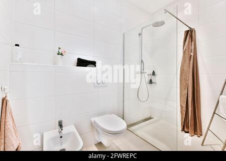 Moderne Innenausstattung des Waschraums mit Duschkabine aus Glas und Weiß Wandtoilette mit Bidet Stockfoto