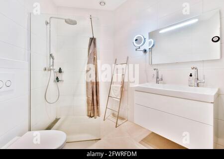 Moderne Innenausstattung des Waschraums mit Duschkabine aus Glas und Weiß Wandtoilette mit Bidet Stockfoto