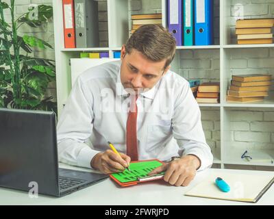 Konzentrierter Mitarbeiter überprüft Daten auf einem Laptop. Geschäftsmann arbeitet mit Bericht. Stockfoto