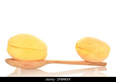 Zwei saftige Ananas-Aprikosen mit einem Holzlöffel, Nahaufnahme, isoliert auf Weiß. Stockfoto