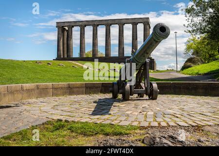 Die portugiesische Kanone mit dem National Monument of Scotland im Hintergrund, Carlton Hill, Edinburgh, Schottland Stockfoto