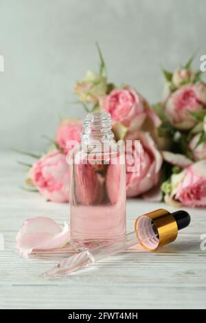 Flasche mit ätherischem Rosenöl auf weißem Holztisch Stockfoto