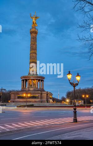 Die berühmte Siegessäule mit Straßenlaterne und Bäumen verzweigt sich in Berlin, Deutschland, in der Abenddämmerung Stockfoto