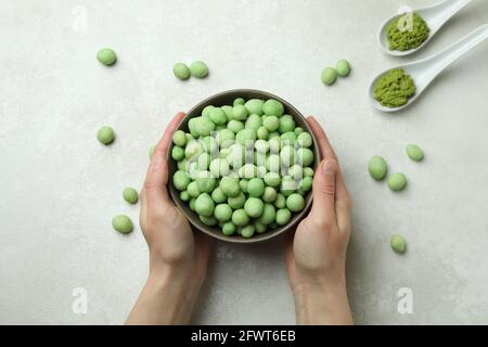 Weibliche Hände halten Schüssel mit Wasabi-Nüssen, Draufsicht Stockfoto