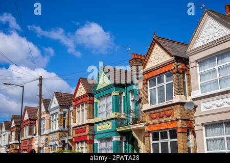 Eine Reihe von bunten Reihenhäusern rund um Kensal erhebt sich in London mit Oberleitungskabeln Stockfoto