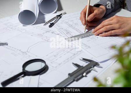 Der Händearchitekt zeichnet mit einem Bleistift eine Skizze eines Designprojekts. Arbeitstisch eines Ingenieurs, der Pläne für ein Gebäude erstellt. Stockfoto