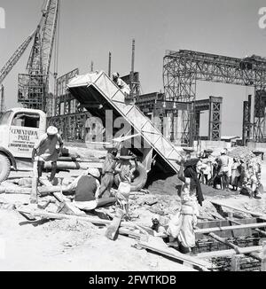 Ende der 1950er-Jahre, historisches Bild des Baus des Durgapur-Stahlwerks, Durgapur, Westbengalen, Indien, mit einer Lieferung von Zement und Arbeiterinnen, die ihn in kreisförmigen Schalen auf ihren Köpfen trugen. Nach der Unabhängigkeit war das Stahlwerk eines der ersten großen Bauprojekte in Indien, und 1957 übernahm ein indisches Unternehmen, Patel Engineering, in Zusammenarbeit mit dem britischen Unternehmen Cementation UK, die gesamten Tiefbauarbeiten. Das riesige Projekt umfasste Bau- und Maschinenfundamente, Betonpfähle, Gebäudestruktur, Bahngleise, Straßen, Abfluss und Wasserversorgung. Stockfoto