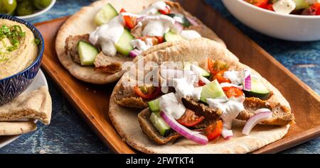 Zwei Gyros mit Gemüse und weißer Knoblauchsoße auf einem Rustikaler Holztisch Stockfoto