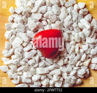 Rotes Herz auf einer Gruppe von weißen Steinen mit Pailletten Stockfoto