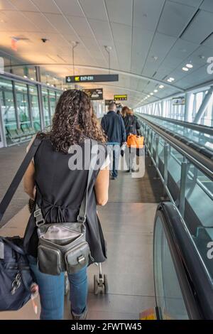 Flughafen Lester Pearson, Toronto, Kanada, Februar 2016 - Junge Frau hinter anderen Flugreisenden, die zum Boarding Gate für ihren Flug gehen Stockfoto