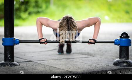 Frau macht Liegestütze an einer Bar im Freien Stockfoto