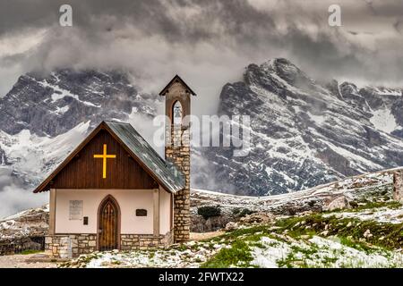 Cappella degli Alpini (Alpini-Kapelle) mit Dolomitengipfeln im Hintergrund nach einem sommerlichen Schneefall , Tre Cime di Lavaredo, Auronzo di Cadore, Italien Stockfoto