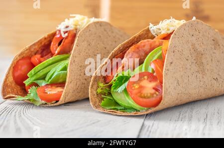 Tacos mit Schinken und Gemüse auf dem servierten Holzteller Stockfoto