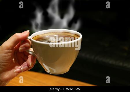 Tasse aromatischen heißen Kaffee mit ansteigendem Dampf im Damencafé Hand Stockfoto